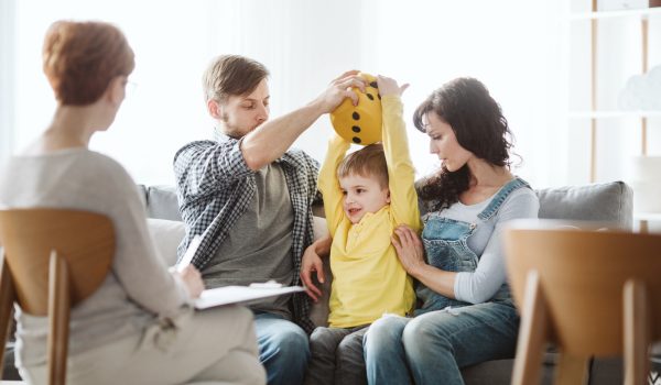 Young family in therapy for a young boy with ADHD who is wearing a yellow top